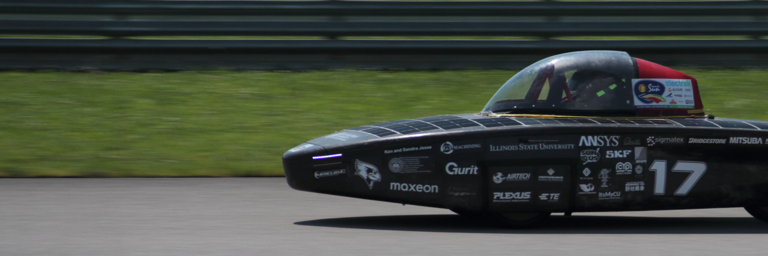 A black solar car on a racetrack.